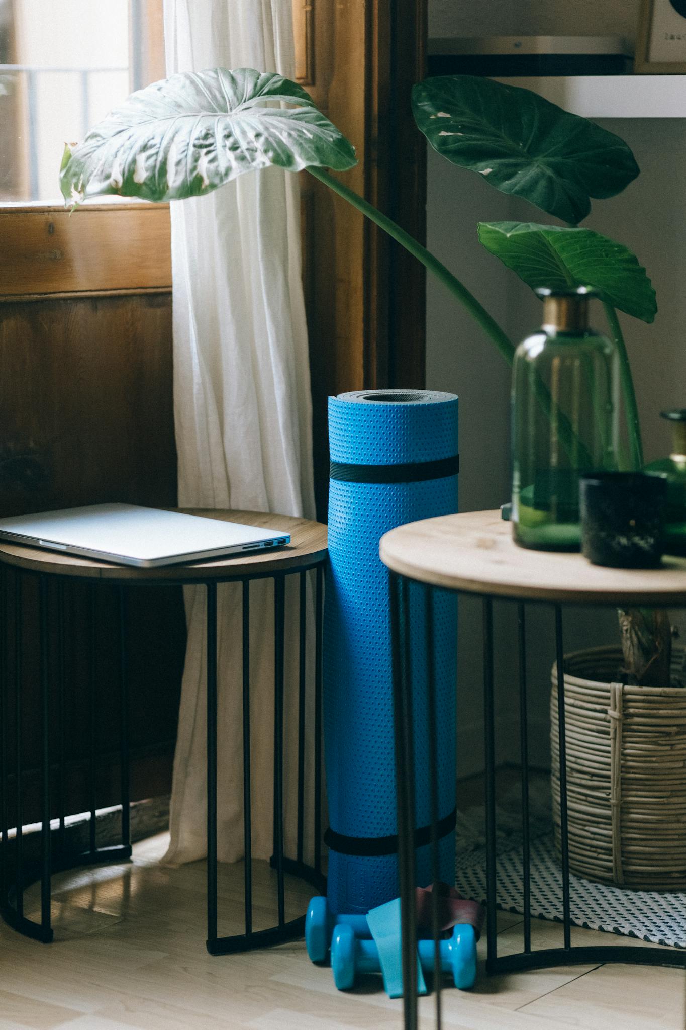 A cozy home office corner with yoga mat, weights, and plants by the window.