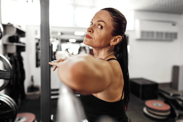 Fit woman doing squats with barbell in a modern gym